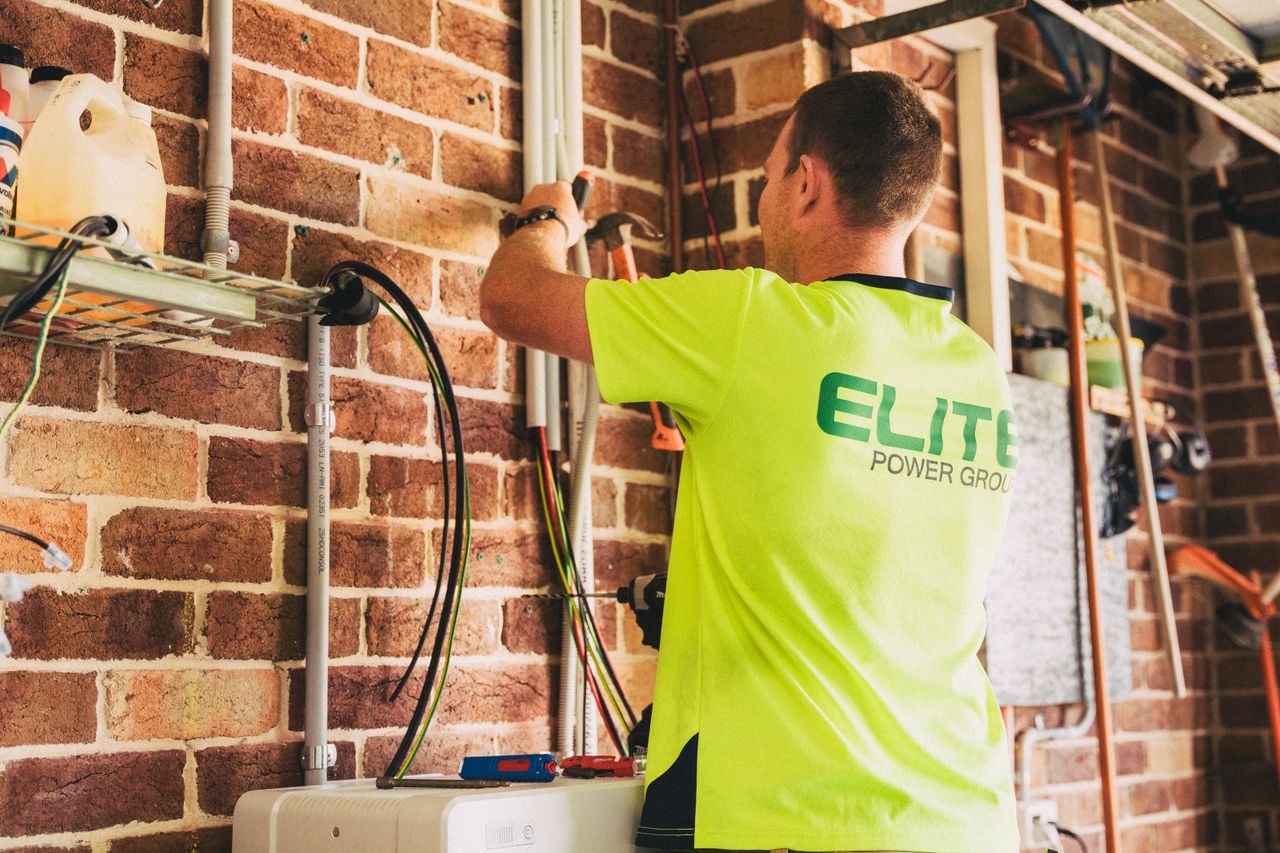 Electrician performing solar battery installation for sustainable energy storage in a home setting.