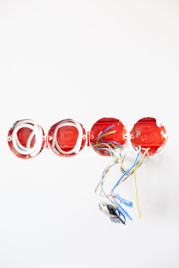 Detailed view of exposed electrical wiring for home renovation on a white wall.